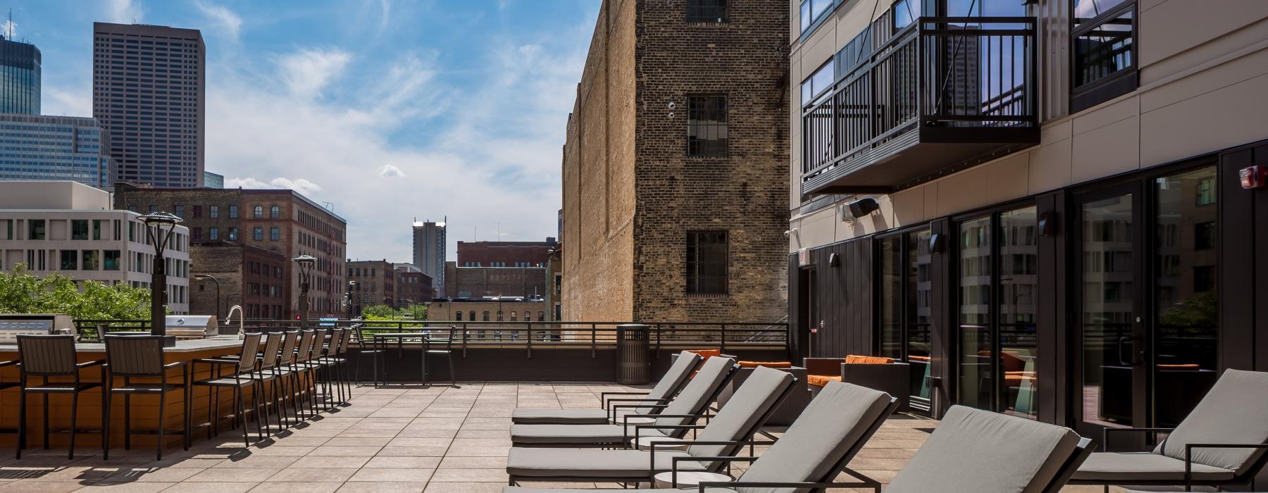 Terrace with lounging areas, grilling station, and bar at Velo upscale apartments in Minneapolis